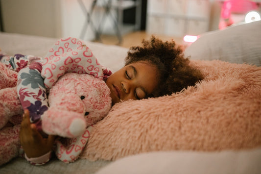 Petite fille noir qui dort dans son lit avec une veilleuse pour enfant