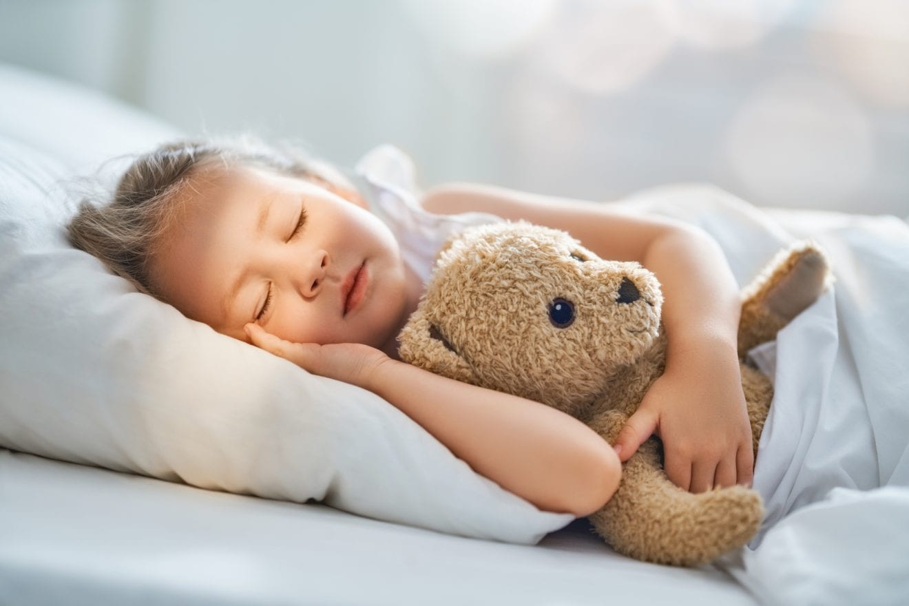 Bébé fille qui dort sur le côté avec son ours en peluche dans les bras