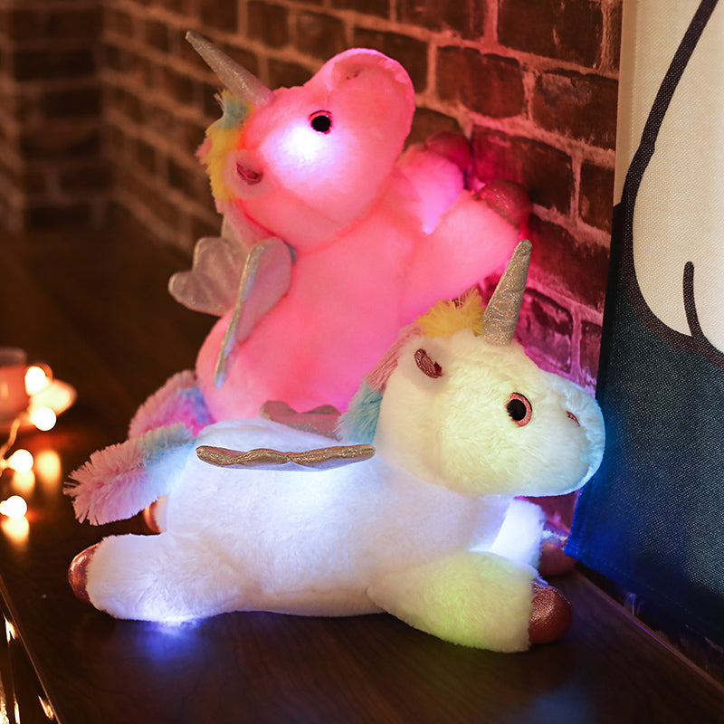 Deux doudous en formes de licornes lumineuses, l'un de couleur rose et l'autre de couleur blanche