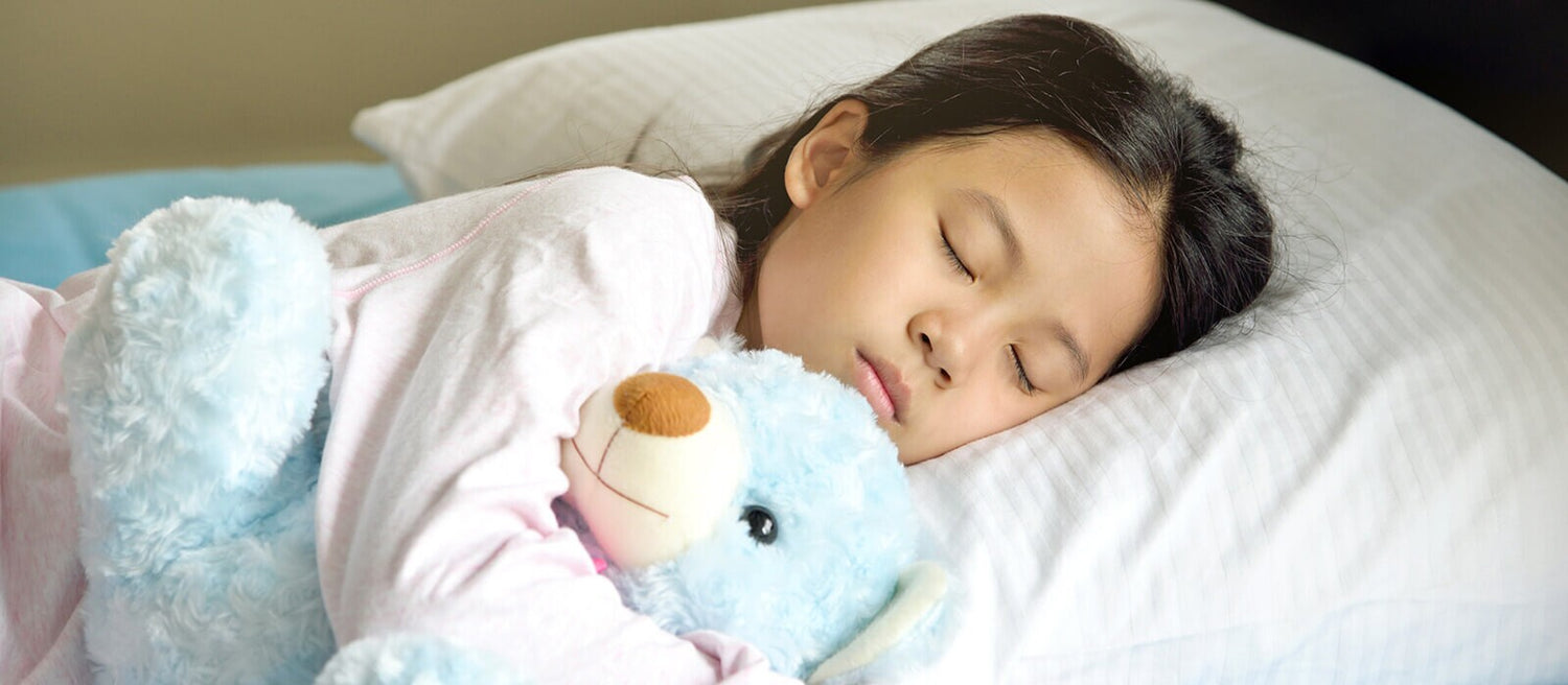 Petite fille qui dort avec sa peluche en forme d'ours bleu