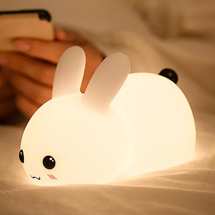 Petite veilleuse en forme de bebe lapin avec la fonction lumineuse activée avec une teinte chaude