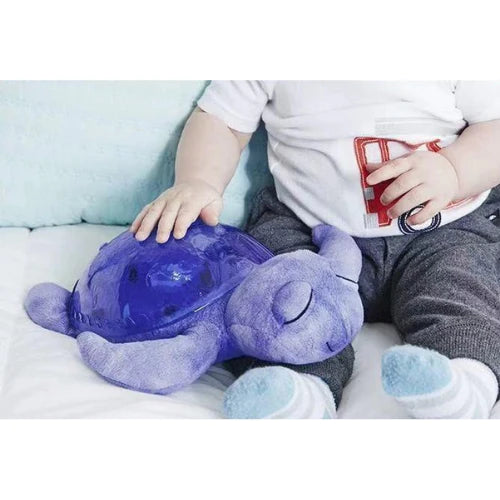 Veilleuse en forme de tortue violette positionnée sur les genoux d'un bebe garçon