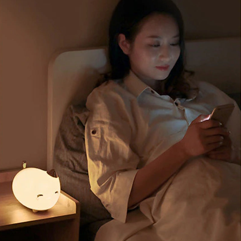 Lampe veilleuse en forme de bébé chat posée sur une table de nuit