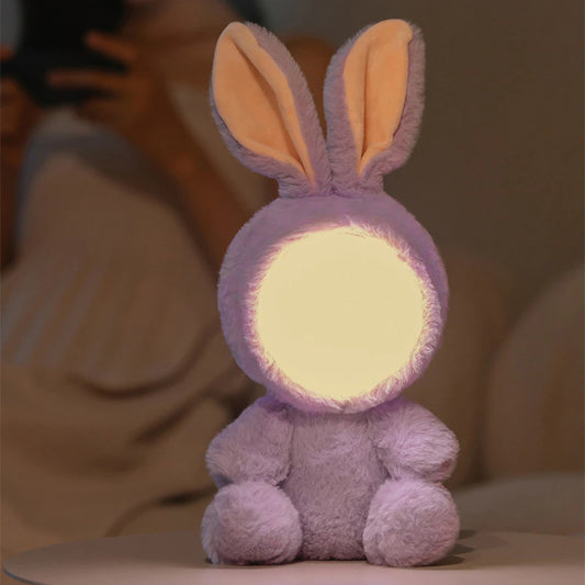 Peluche veilleuse en forme de lapin violet posé sur une table