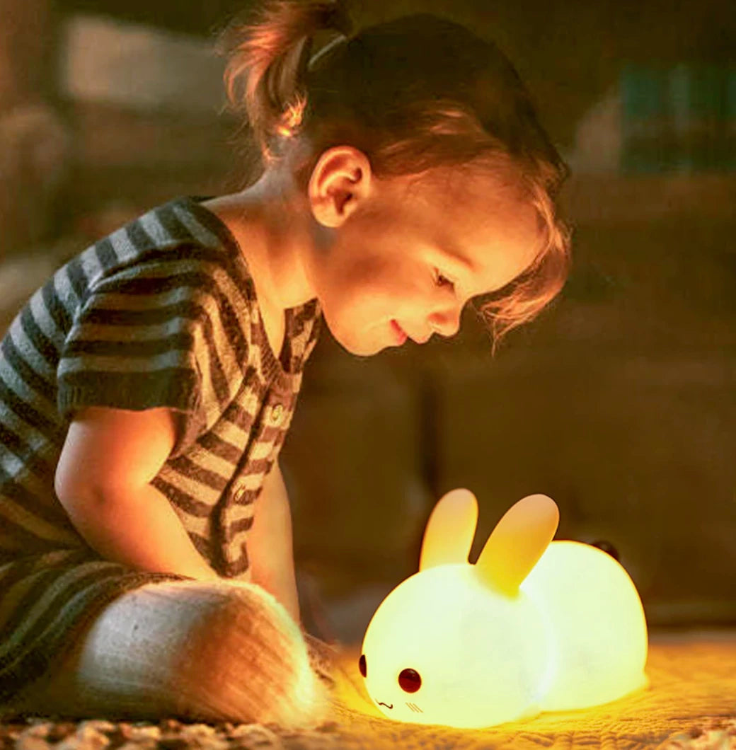 Petite fille qui joue avec sa petite veilleuse en forme de bebe lapin