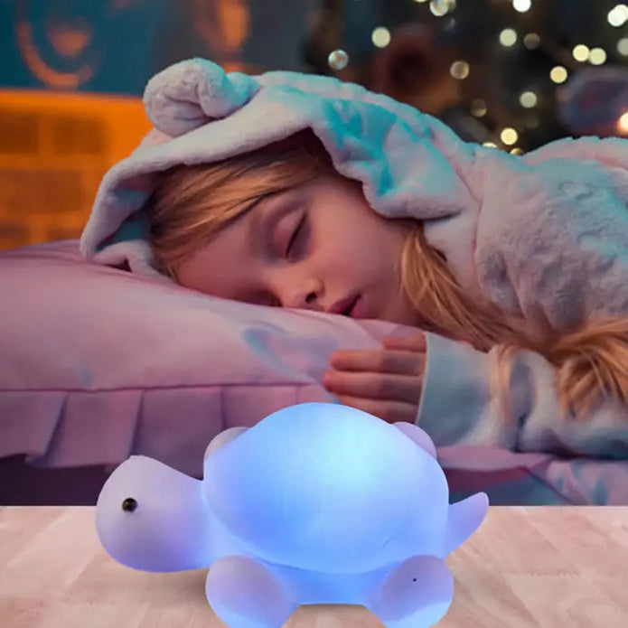 Petite veilleuse en forme de tortue bleue positionnée devant une petite fille qui dort