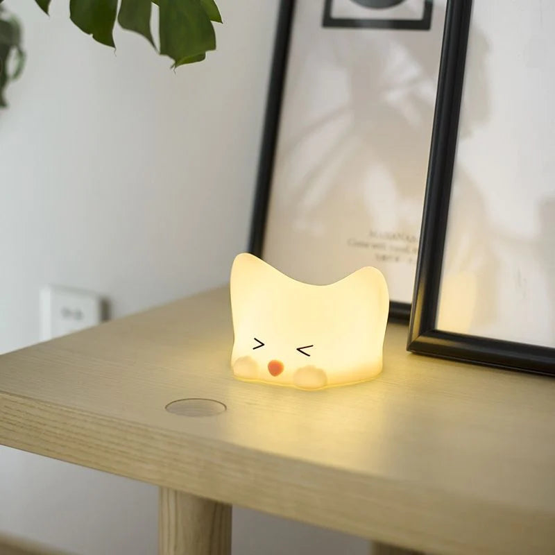 Veilleuse en forme de bébé chat lumineux posée sur une table
